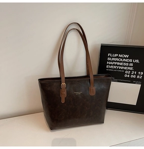 Detailed view of vintage oil wax leather texture and gold logo on a large tote bag