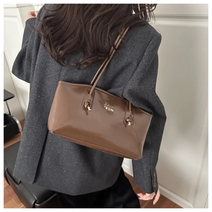 Close-up of deep brown glossy tote bag featuring gold POIN 2DN logo and polished finish