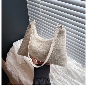 Detailed texture of off-white faux shearling fabric and leather strap on a hobo bag