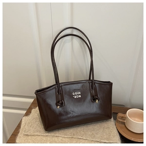 Detail of dark brown oil wax leather tote bag with white lettering and knotted strap