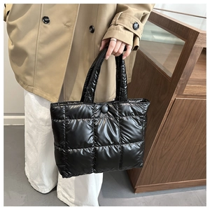 Détail d'un sac cabas noir matelassé aspect doudoune avec finition brillante et bouton
