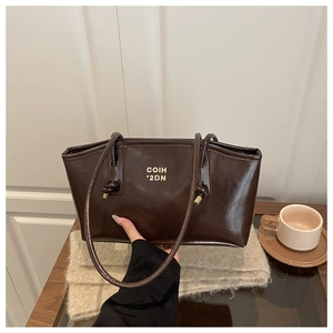 Detail of dark brown tote bag in oil wax leather with gold COIH '2DN text and dual handles