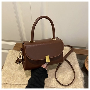 Detail of vintage brown leather handbag with gold buckle and shoulder strap