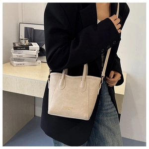 Model wearing a cream vintage tote bag with adjustable strap and gold brand lettering