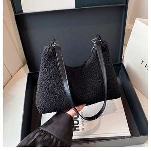 Dettaglio borsa a tracolla in peluche nera in una confezione regalo di lusso elegante