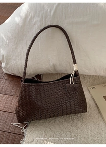 Détail du cuir tressé marron foncé sur un sac à bandoulière rétro minimaliste pour femmes