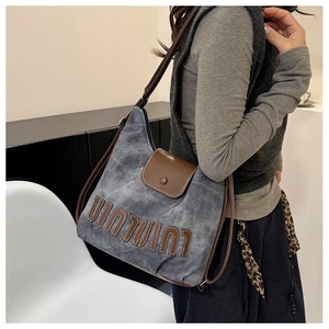 Detailed macro view of grey canvas texture and brown leather logo on casual hobo bag
