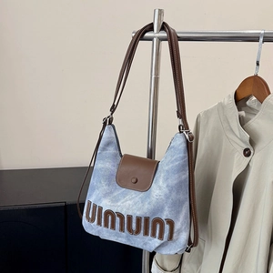 Blue denim tote bag with brown leather trim and large letter patch for casual commuting
