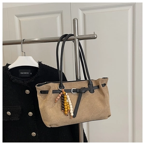 Detail of khaki suede tote bag with decorative wooden bead tassels and buckled straps