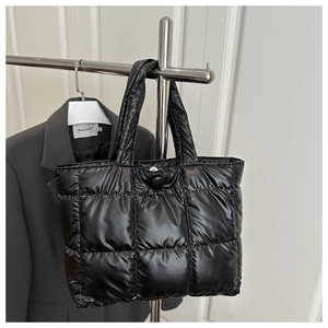 Détail du grand sac cabas noir matelassé avec poignées rembourrées et bouton de fermeture