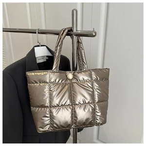 Gros plan du sac cabas matelassé doré champagne avec éclat métallique et boucle ronde