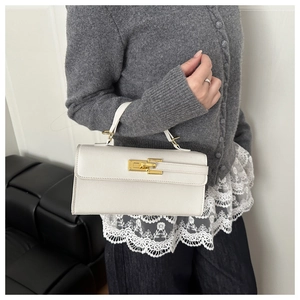 Détail du sac à main en cuir grainé blanc avec fermoir pivotant en métal doré et poignée