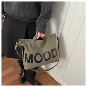 Dettaglio della borsa in tela verde militare con logo MOOD e manici resistenti