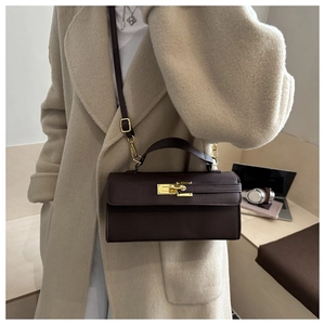 Détail d'un mini sac Kelly marron foncé avec fermoir doré porté par un mannequin
