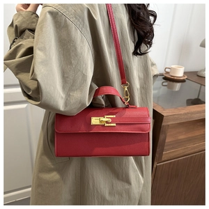 Détail d'un mini sac rouge texturé avec boucle dorée et bandoulière amovible