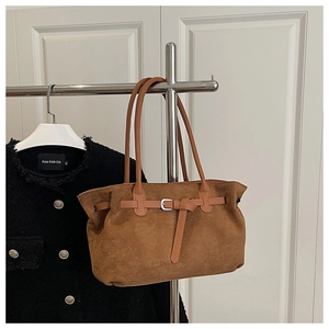 Close-up of brown suede tote bag featuring silver buckle detail and minimalist texture