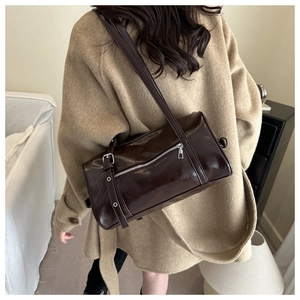 Détail d'un sac polochon marron foncé vintage en cuir PU brillant avec boucle argentée
