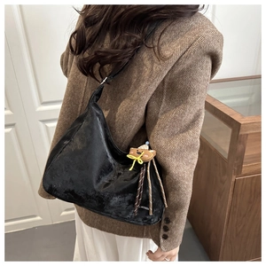 Detail of black semi-circle hobo bag with vintage leather texture and bear charm