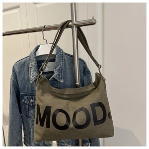 Dettaglio borsa tote in tela verde militare con scritta MOOD su un gancio in metallo