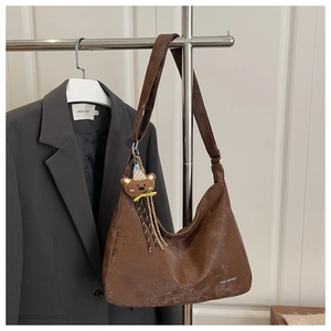 Close-up of vintage brown crossbody bag with distressed leather texture and bear charm