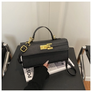 Détail d'un mini sac noir avec fermoir doré tournant et bandoulière en cuir amovible