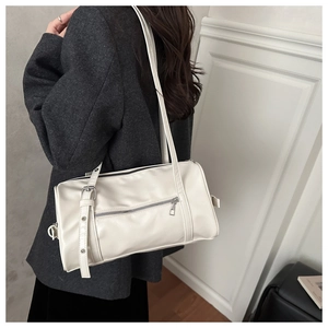 Détail du sac cylindrique blanc cassé en similicuir texturé avec poche zippée élégante