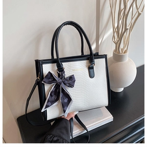 Detailed view of white snakeskin texture tote bag with silk scarf on the handle
