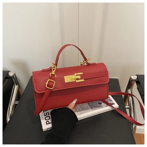 Détail d'un sac à main rouge en cuir Saffiano avec fermoir doré sur un siège noir