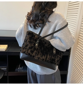 Detailed view of black faux fur tote bag with leather base carried by a model