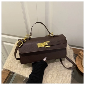 Détail du sac en cuir litchi marron foncé avec fermoir doré rotatif et texture grainée