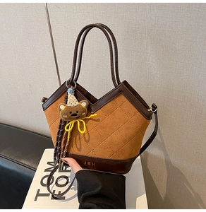 Detail of brown quilted suede bucket bag with bear charm on a Tom Ford book