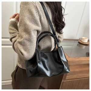 Detail of a black pleated leather bucket bag shown being worn as a shoulder bag
