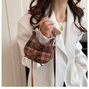 Close-up of mini checkered crossbody bag with bows on a white blazer model style