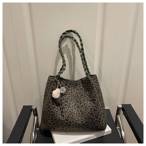 Detalle de bolso tote con estampado de leopardo verde oscuro y asas tejidas con colgante