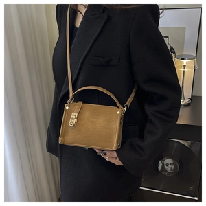 Detailed side view of caramel textured shoulder bag with golden clasp and metal rivets
