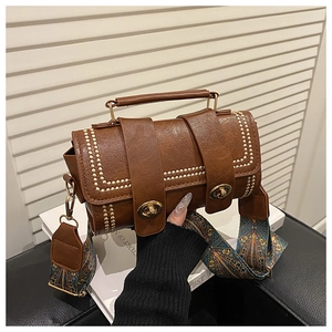 Detail of brown vintage PU bag with gold studs and colorful ethnic shoulder strap