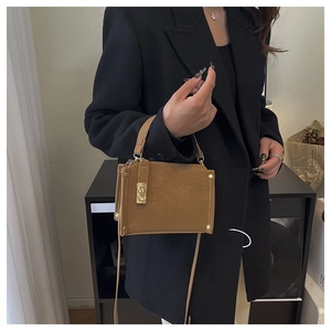 Detail of caramel faux leather bag with gold buckle and textured finish on a black blazer