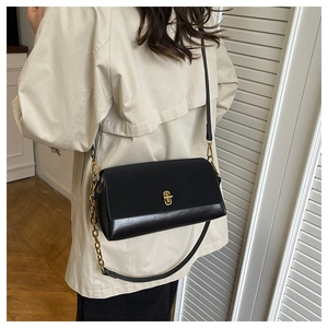 Detail of black oil wax leather crossbody bag featuring gold metal lock and chain strap