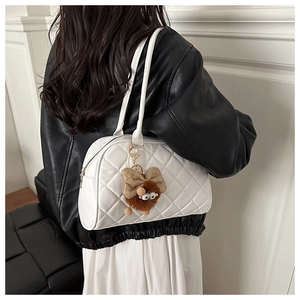 Detail of white quilted bowling bag with rhombus pattern and brown plush charm