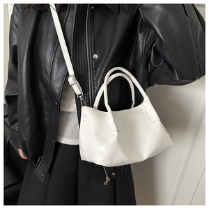 Close-up of white leather bucket bag showing adjustable strap and silver metal zipper
