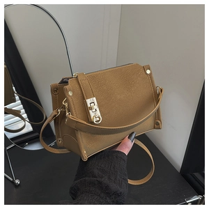 Detailed mirror view of brown leather handbag featuring gold metal clasp and buckle hardware
