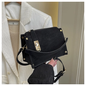 Detail of black textured leather bag featuring golden twist lock and metallic studs