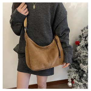 Brown suede tote bag with wide strap and fringe detail shown on a model in winter