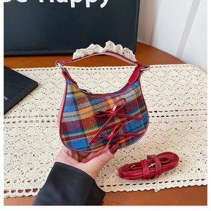Close-up of mini crescent bag with multi-color plaid pattern and red bow accent