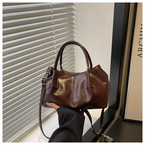 Detailed macro view of dark brown pleated leather bucket bag with silver metal hardware