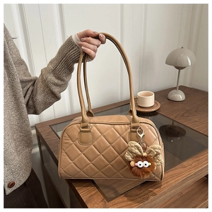 Close-up of caramel quilted PU leather handbag with a plush mascot charm decoration