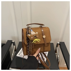 Detail of vintage brown leather backpack with cartoon bear charm and gold buckle clasp