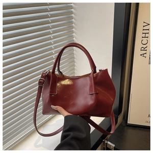 Detail of burgundy glossy tote bag featuring silver hardware and adjustable shoulder strap
