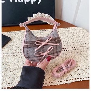 Close-up of mini pink plaid handbag featuring leather bows, lace trim and crossbody strap