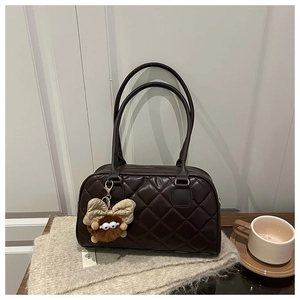 Detail der dunkelbraunen Stepptasche mit lustigem Plüsch-Anhänger im Herbst-Stil